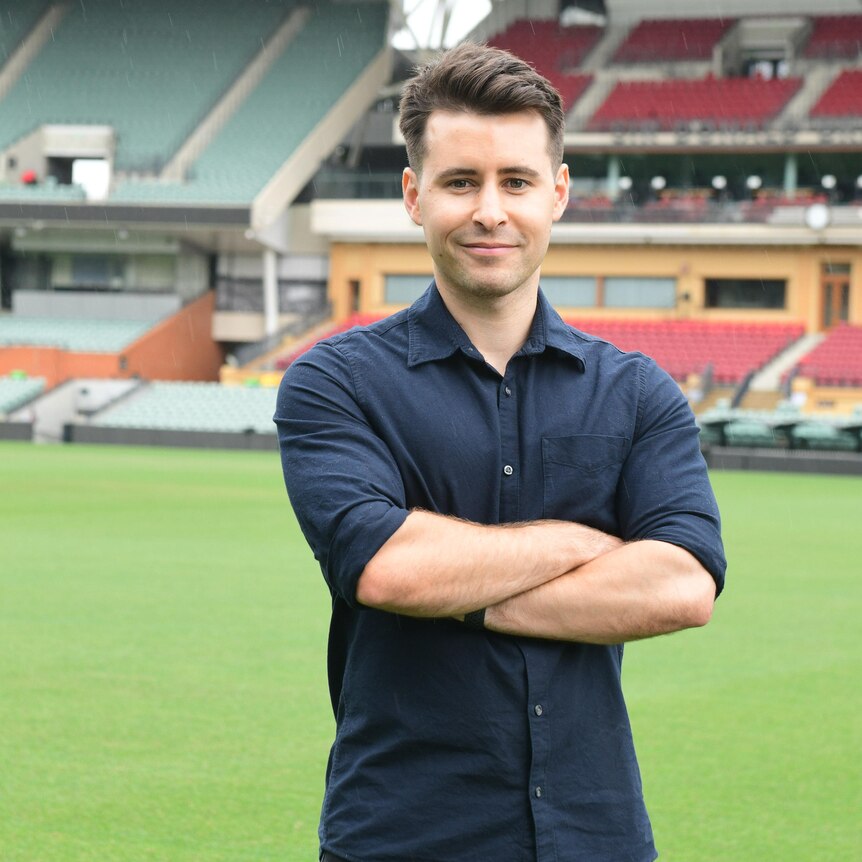 Aaron Bryans, standing in the middle of the Adelaide Oval, with an empty grandstand behind him.