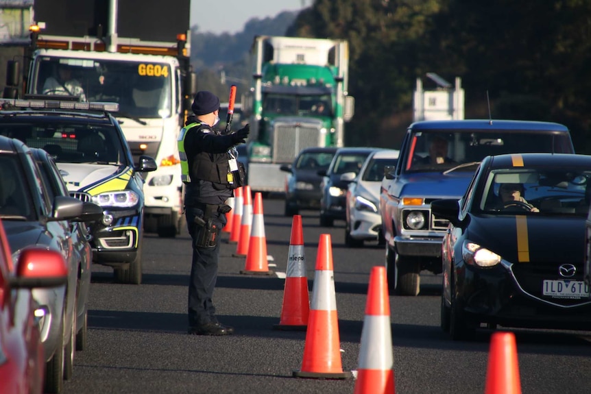 A police officer directing two lanes of busy traffic.