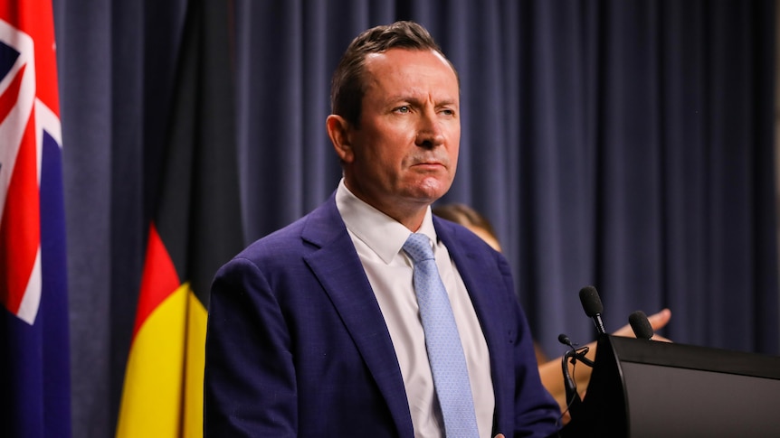Mark McGowan stands at a lectern, looking into the distance.