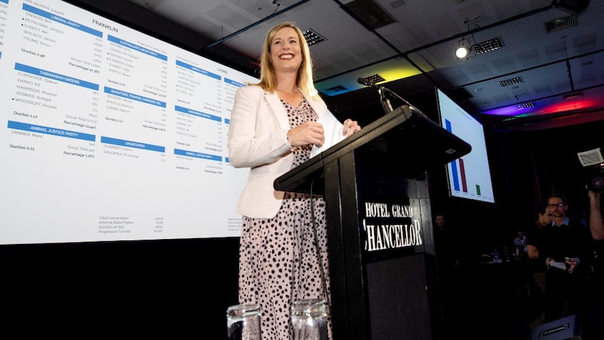 a blonde woman stands on a stage