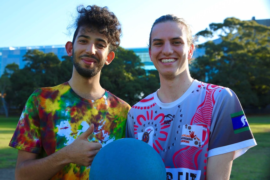 Two young men standing in a park with a  ball.