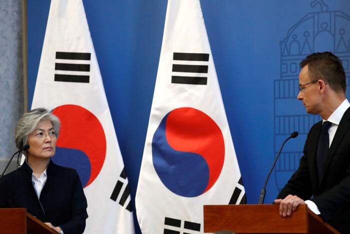 Kang Kyung-wha, left, looks to Peter Szijjarto, right, as the pair hold a press conference with South Korean flag behind them.