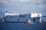 The USNS Mercy departing from a naval station. 