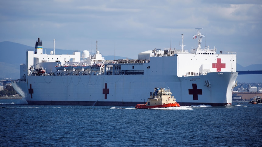 The USNS Mercy departing from a naval station. 