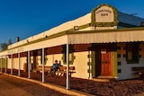 Old man sitting out front of the Birdsville Hotel at dusk