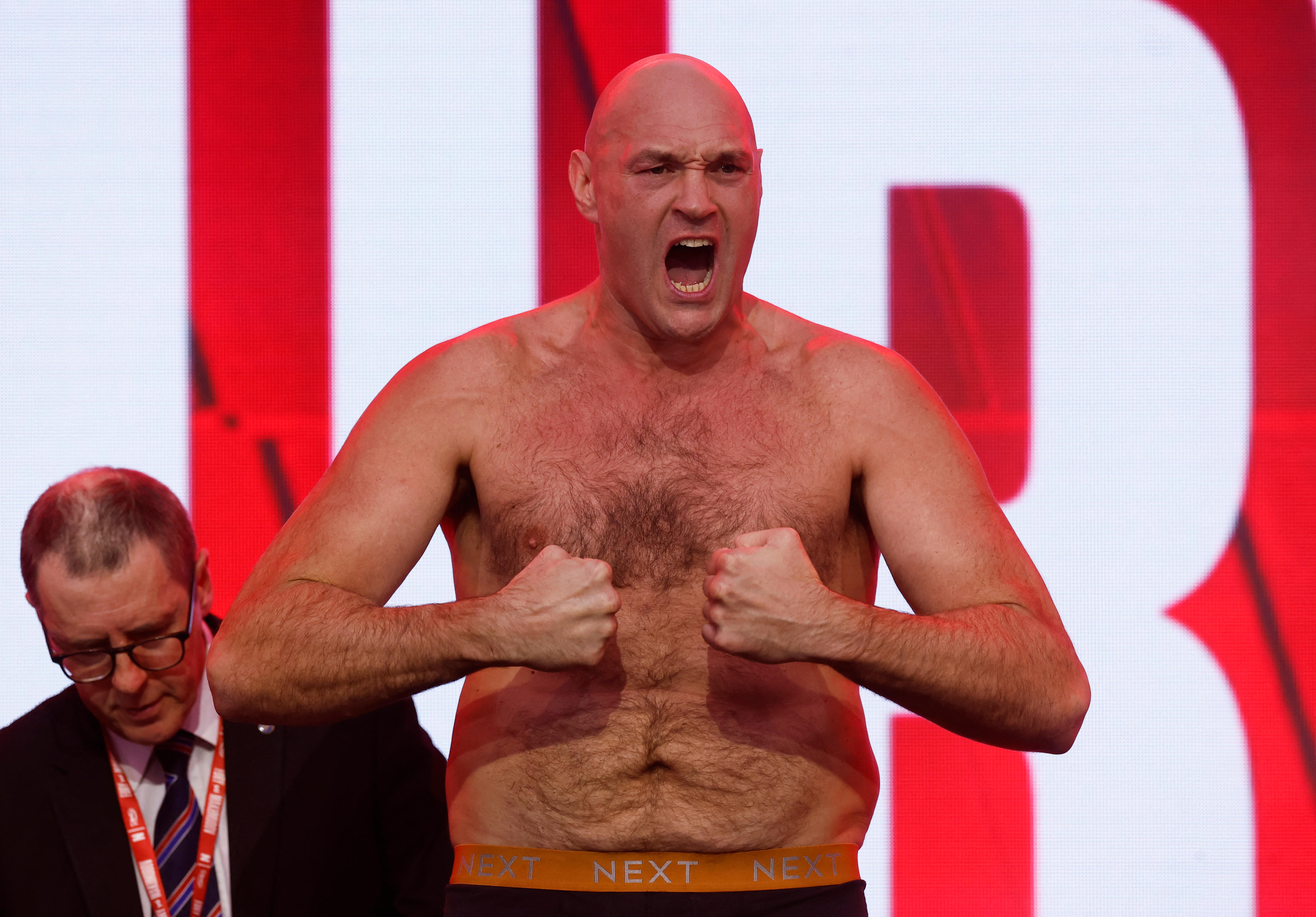 Tyson Fury with no shirt on jeering while flexing his arms with his two fists directed at one another.