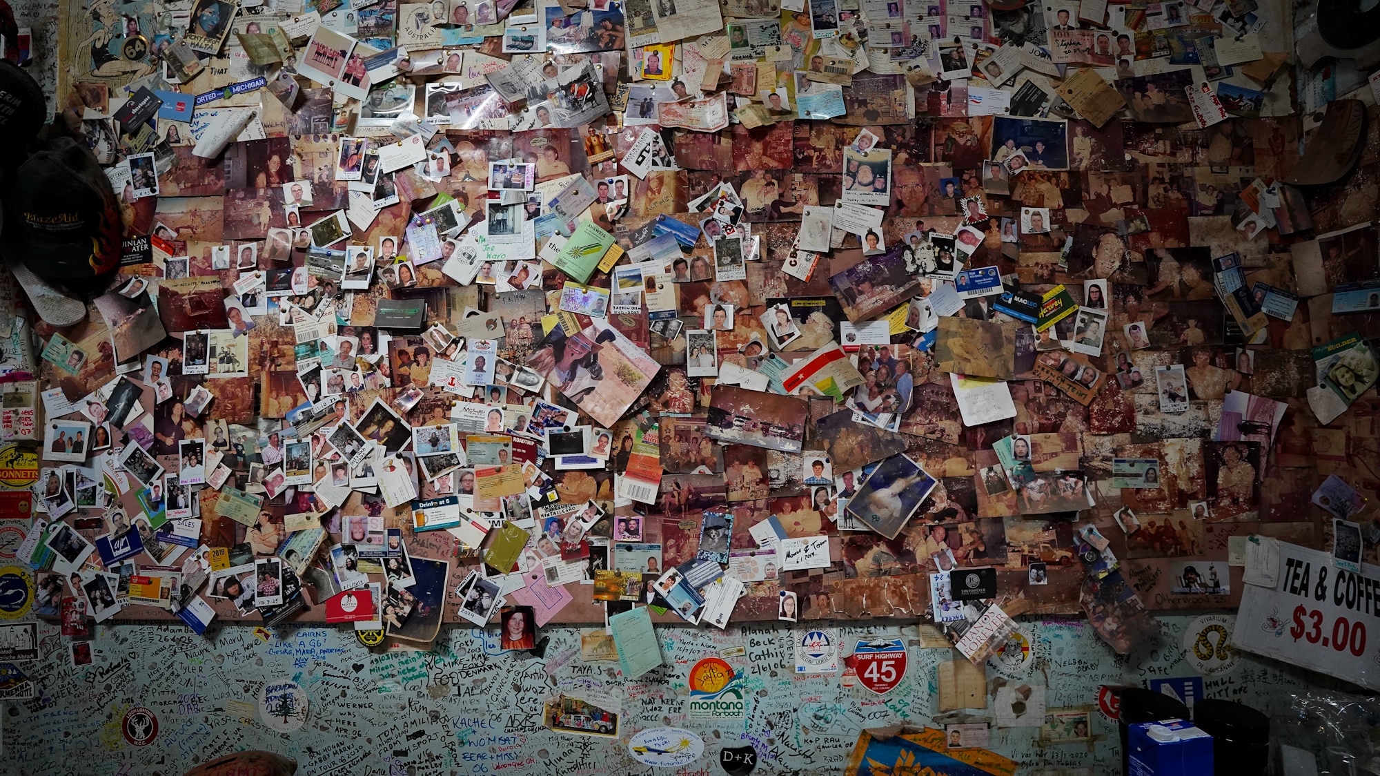A wall inside a hotel is plastered with photos, signatures, business cards, plane tickets and other mementos left my travellers.