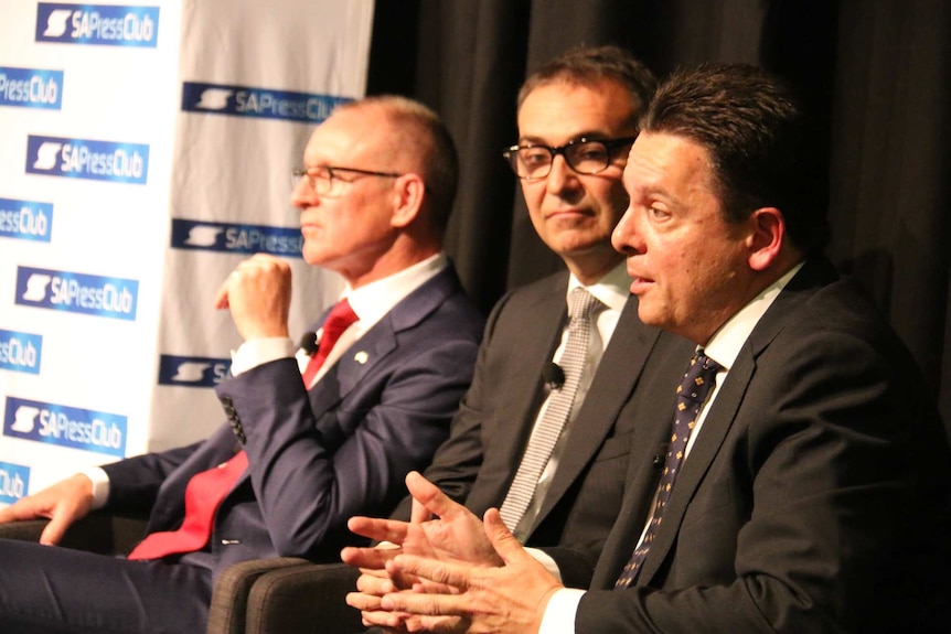 Three men seated in a row.