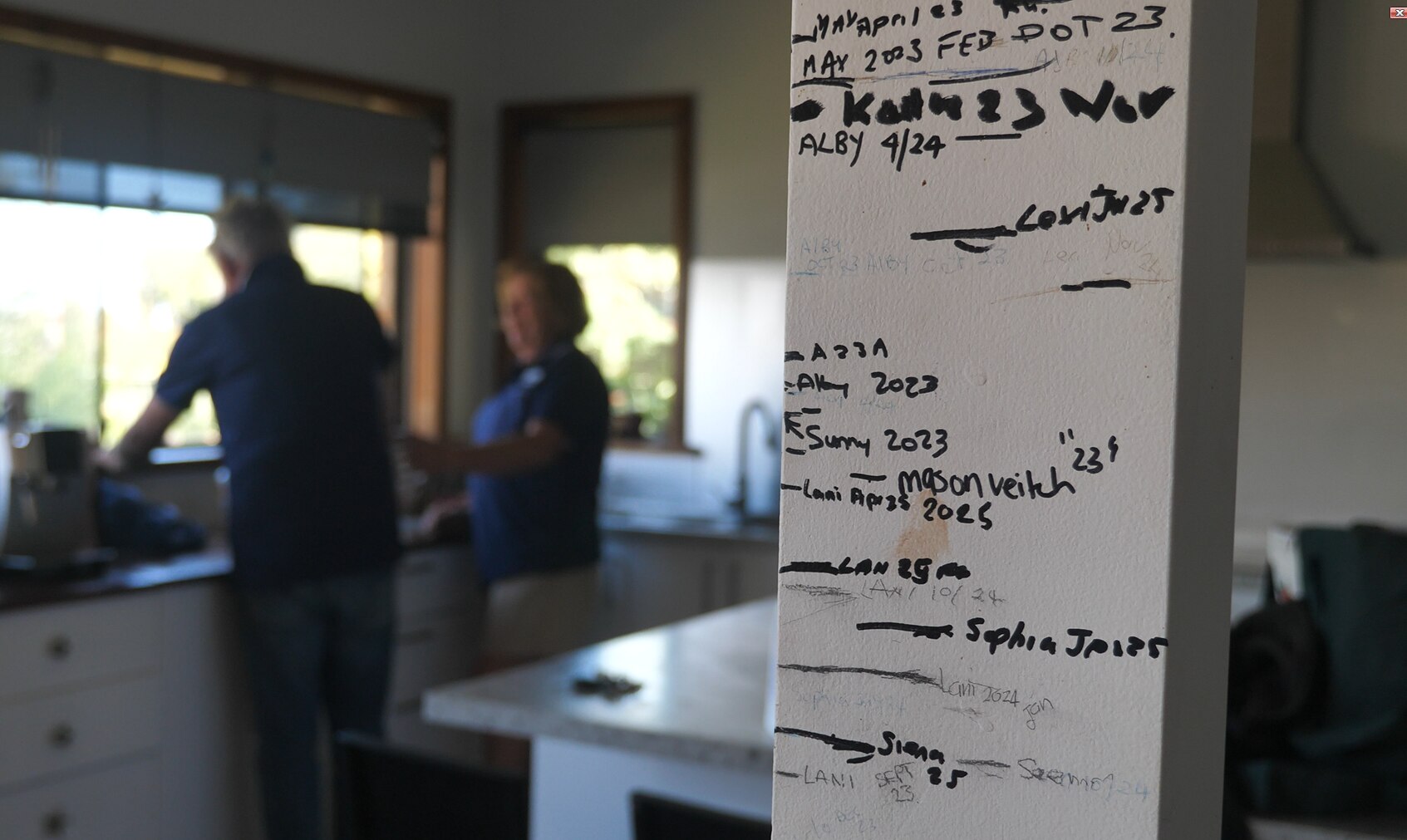 Dentro de una casa, un poste en el primer plano de la foto está cubierto con las medidas de altura de la familia.