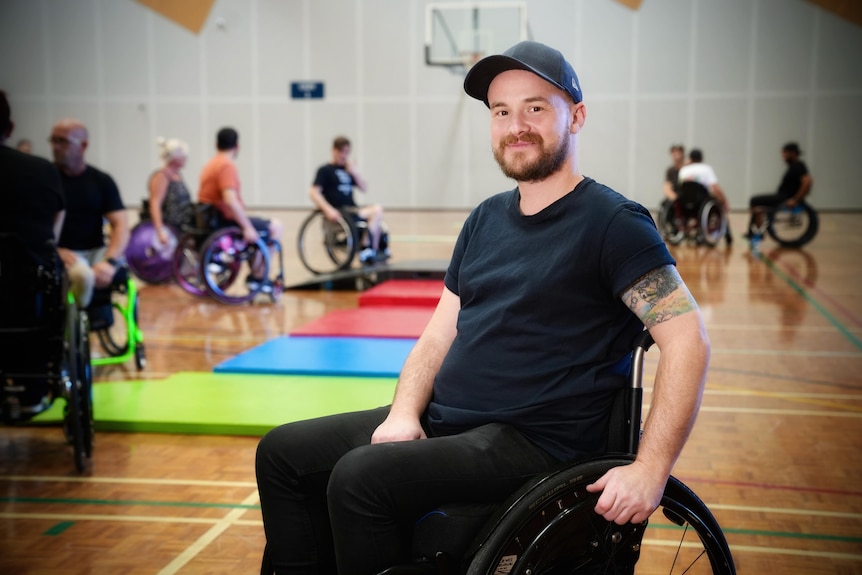 A man named Jack O'Keefe sits in a wheelchair inside a gymnasium.