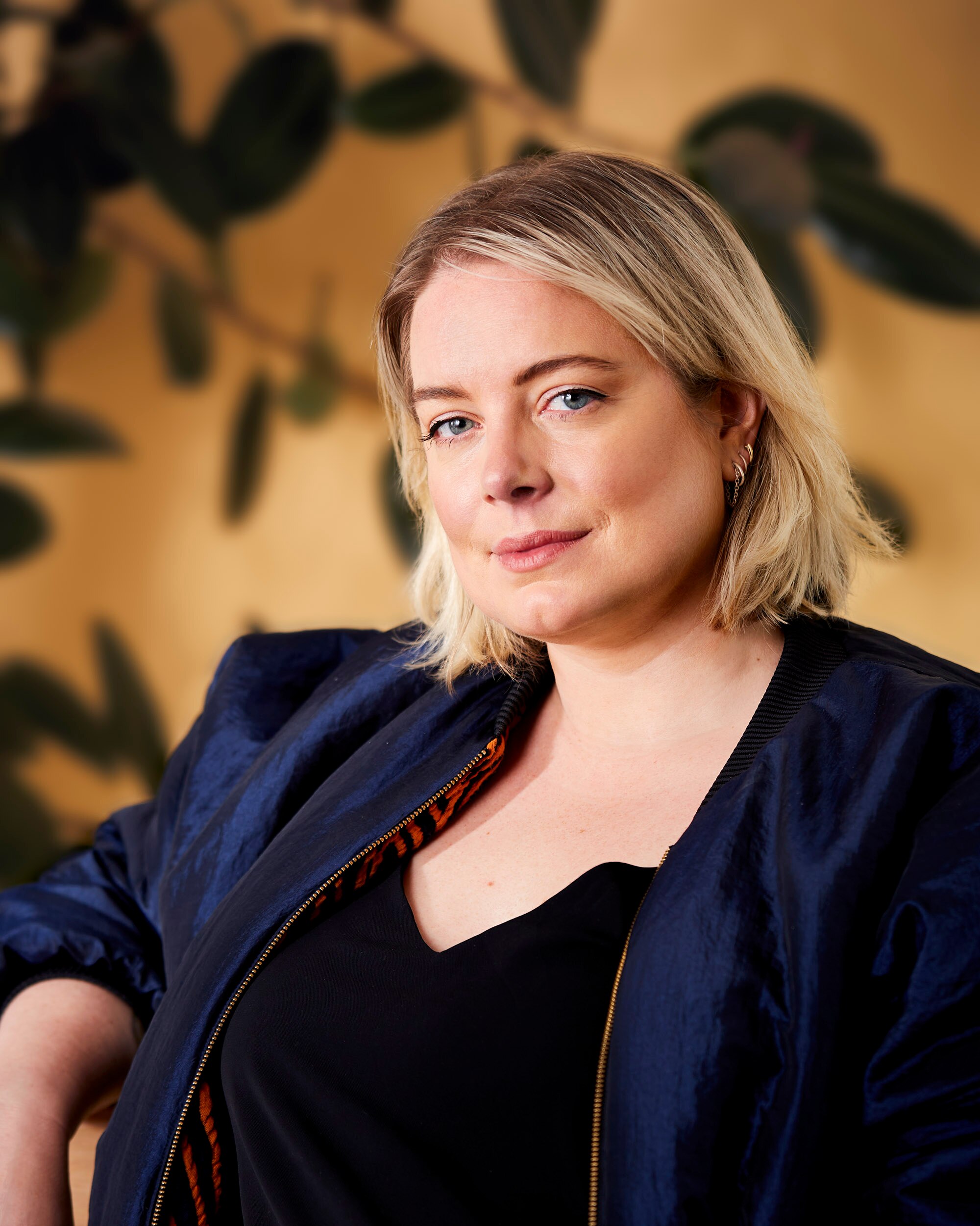 A young white woman with blonde hair and blue eyes wearing a navy blazer