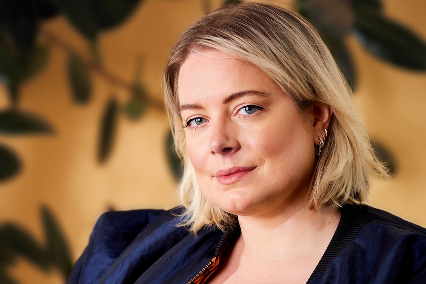 A young white woman with blonde hair and blue eyes wearing a navy blazer