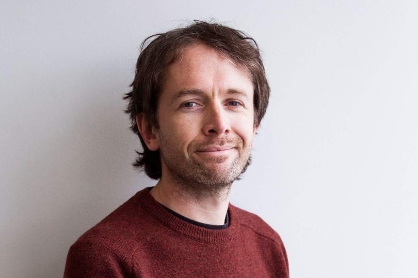 Ryan Monro, wearing a maroon sweater, poses for a portrait