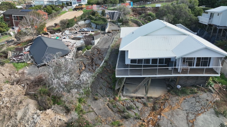 Aerial shot of two homes, one demolished and the other barely standing.  