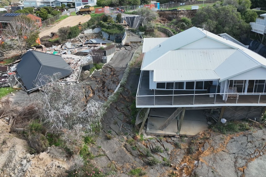 Aerial shot of two homes, one demolished and the other barely standing.  