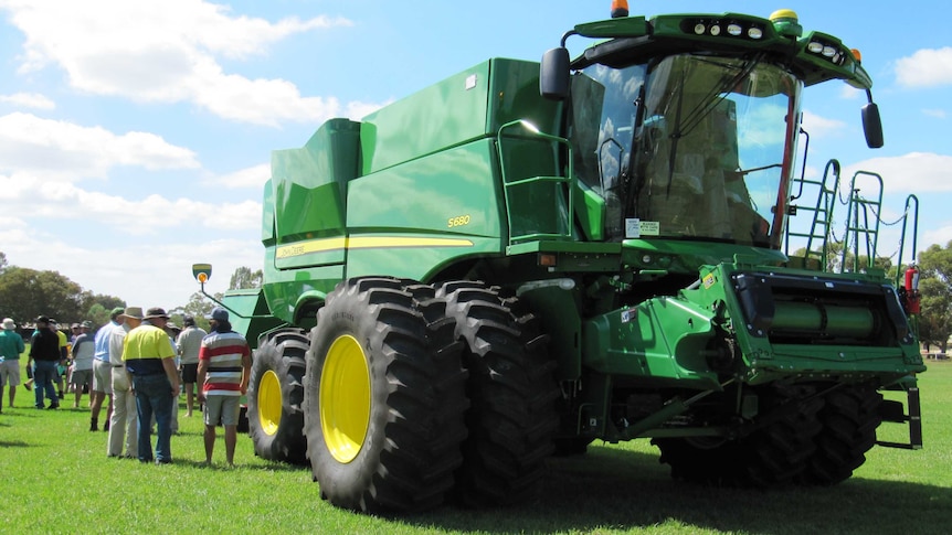 Farmers inspect a large grain header