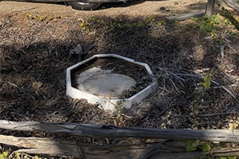 A white septic tank lid in the ground. 