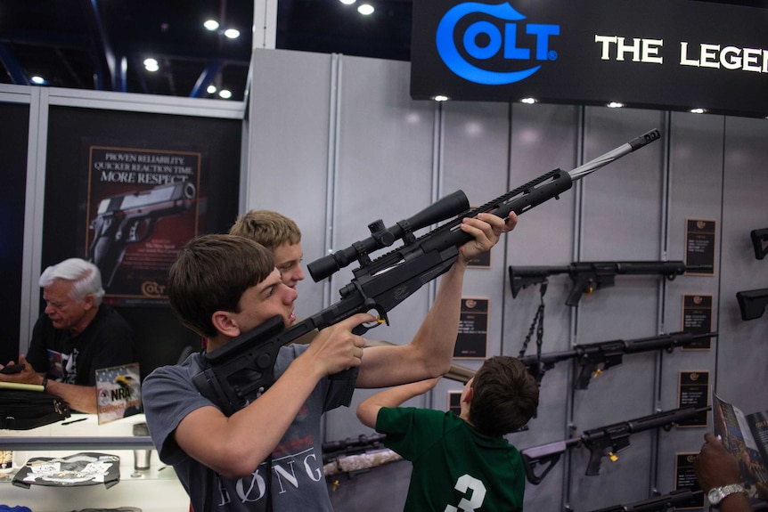 Teenager sizes up Colt rifle at NRA meeting