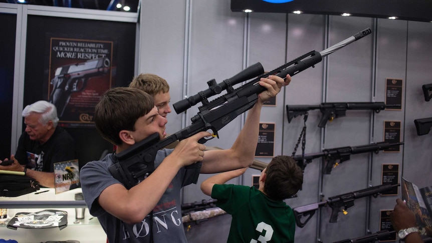 Teenager sizes up Colt rifle at NRA meeting