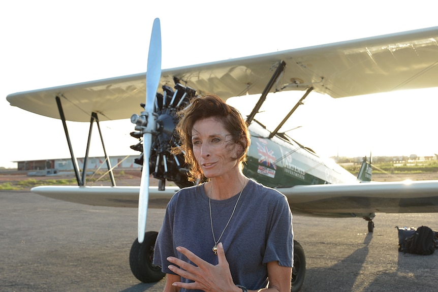 Adventurer Tracey Curtis-Taylor standing in front of 1940s-era biplane.