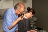 A doctor examines a patient for skin cancer.