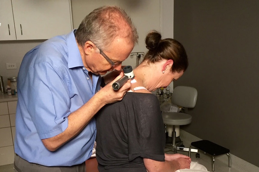 A doctor examines a patient for skin cancer.