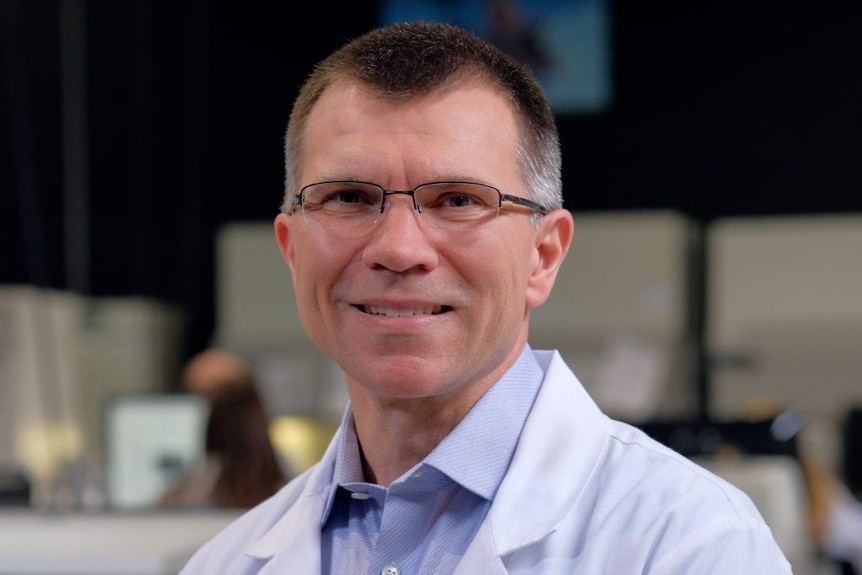 Middle-aged man wearing glasses in white coat