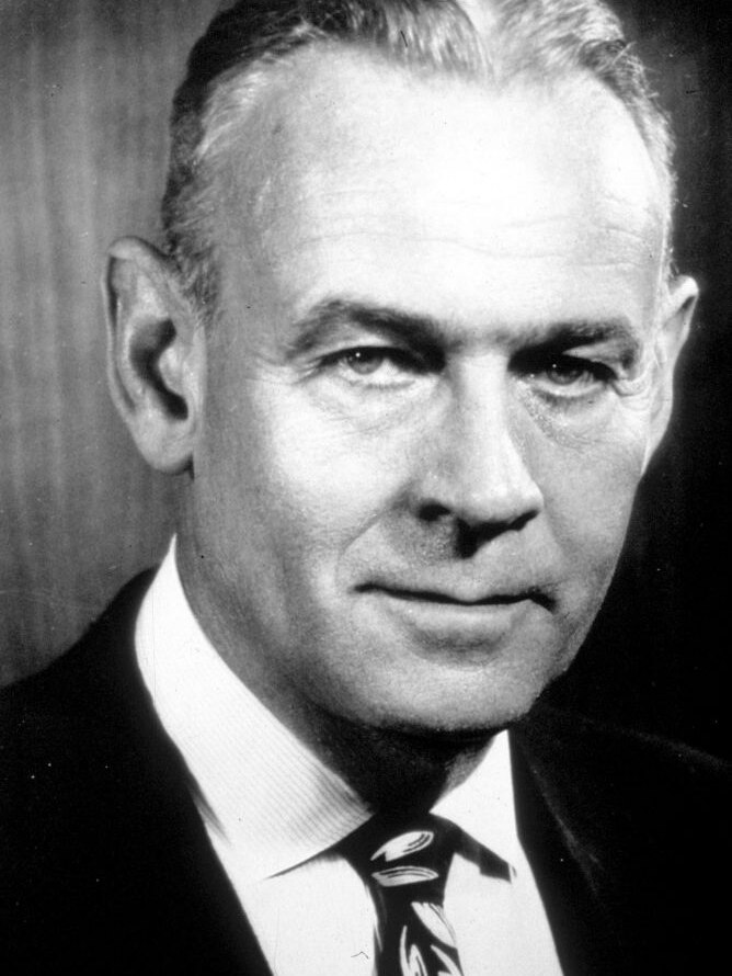 Schwarz-Weiß-Porträt eines Mannes mittleren Alters mit hellen Augen und schwarzem Haar.