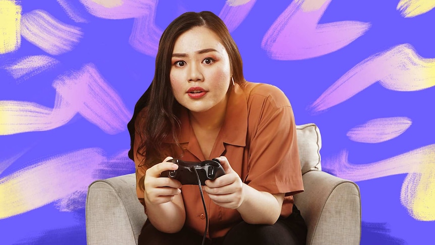 A woman holding a gaming console looking to camera.