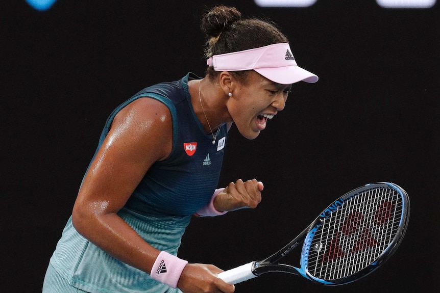 Naomi Osaka pumps her fist as she celebrates winning a point.