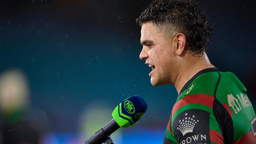 South Sydney Rabbitohs' Latrell Mitchell, seen from the side, speaks into a Fox Sports microphone after an NRL game.