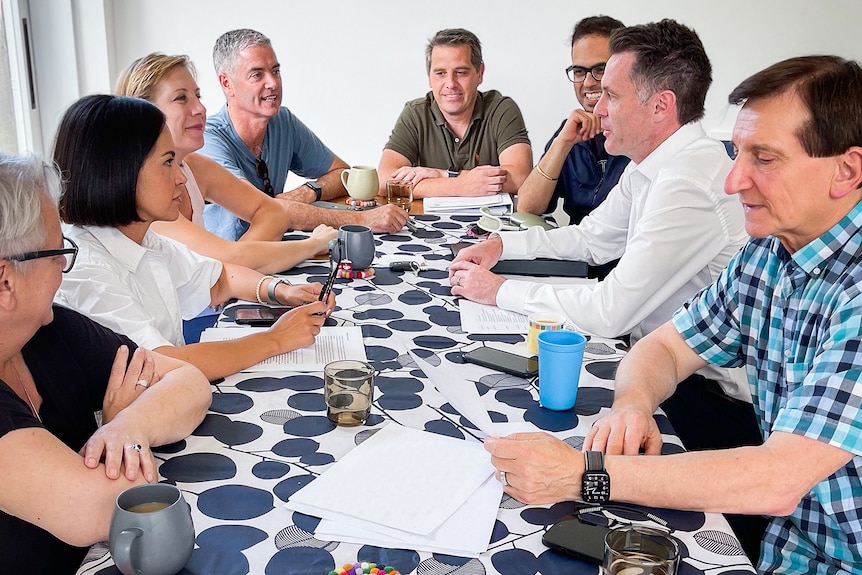 a group of men and women sitting around a table talking