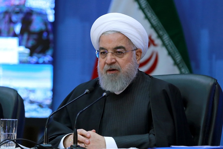 President Hassan Rouhani speaking into a microphone.