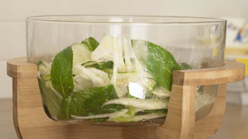 A clear, glass bowl of fennel salad with mint and zucchini.