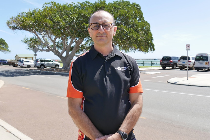 Mid shot of a man in a polo shirt with a beach in the background. 