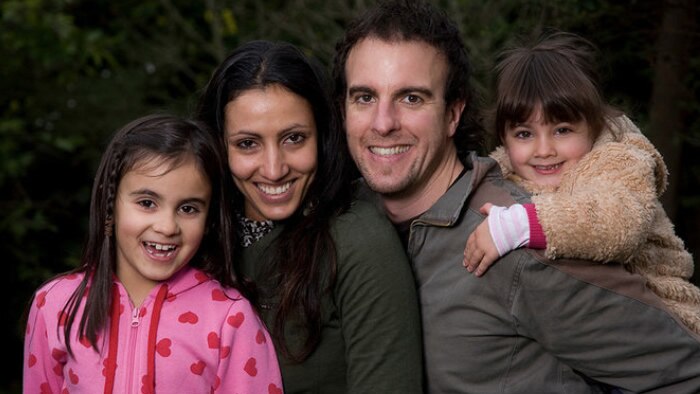 A family of four; Mum, Dad and two daughter pose for a portrait