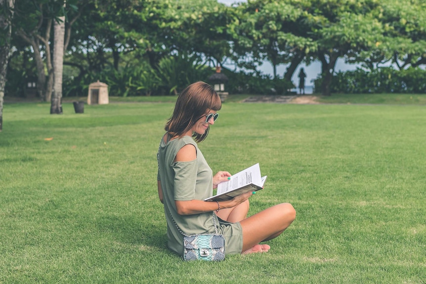 woman reading book in park