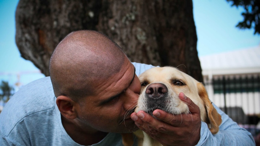 Larry Marshall sitting and hugging his guide dog Rufus