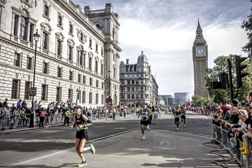 A woman running ahead of other runners on the streets of London. 