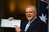 Prime Minister Scott Morrison holds up a Coronavirus Isolation Declaration Card.