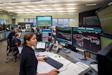 Workers in front of banks of computers and monitors remotely running operations at  Rio Tinto iron ore mines in WA