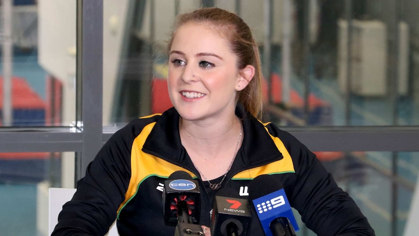 WA gymnast Lauren Mitchell mid shot, sits behind desk with with microphones on.