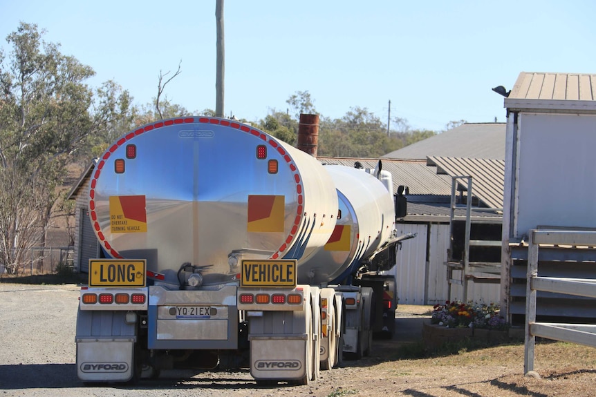 A milk truck pulled up next to a dairy shed.