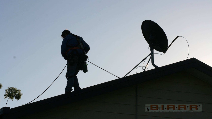 Silhouette of man on roof installing wires