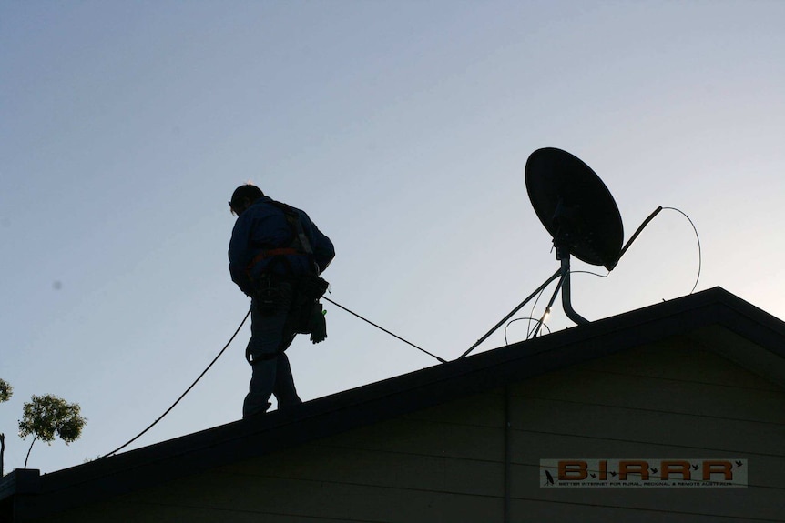 Silhouette of man on roof installing wires