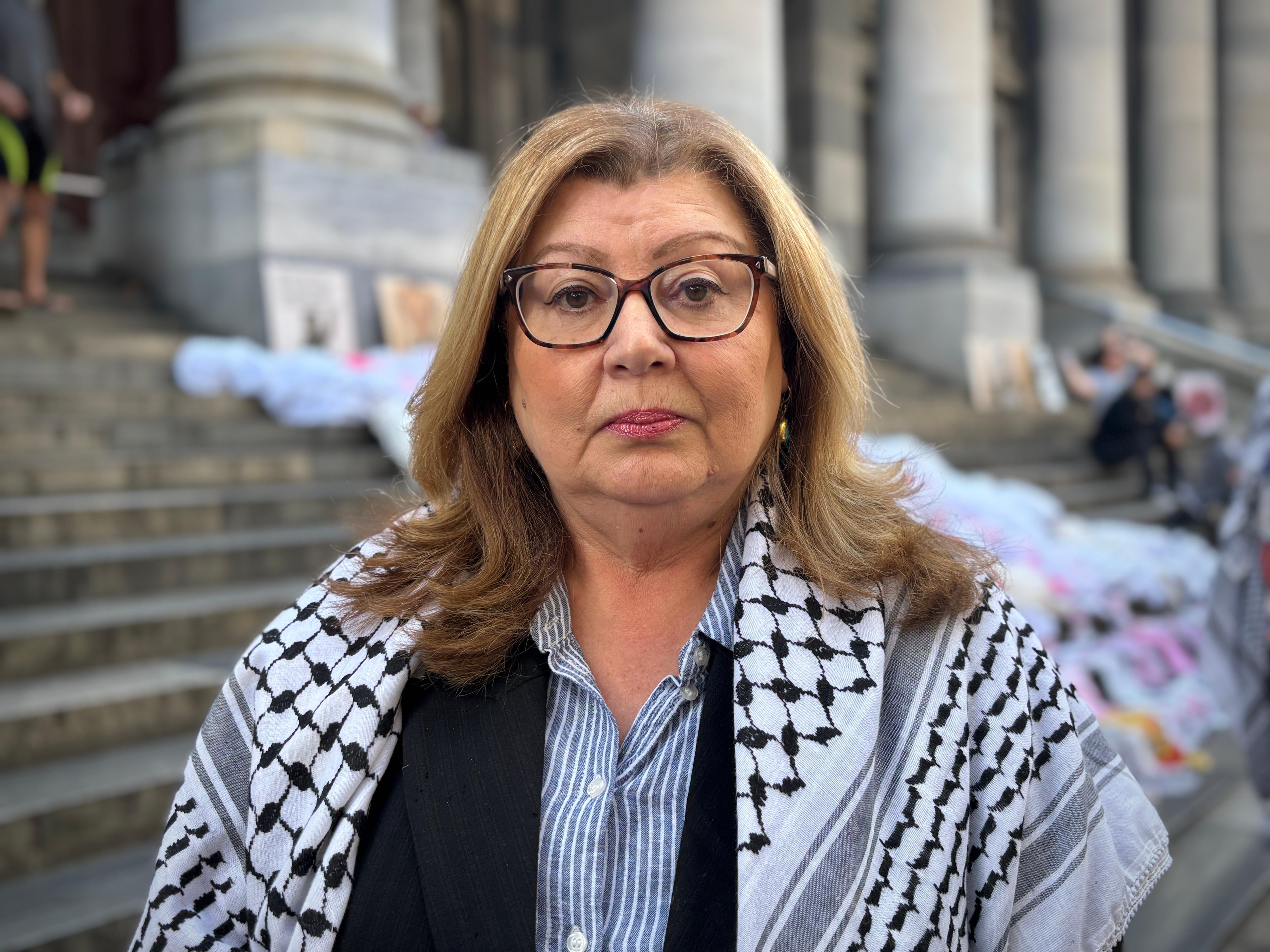 A woman with brown hair and glasses wearing a shawl looks into the camera.