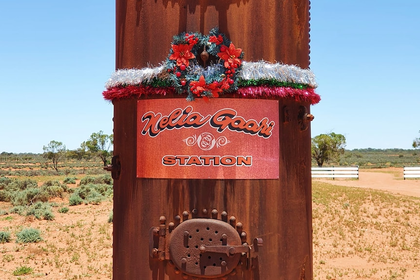 a sign that says nelia gaari station with christmas tinsel