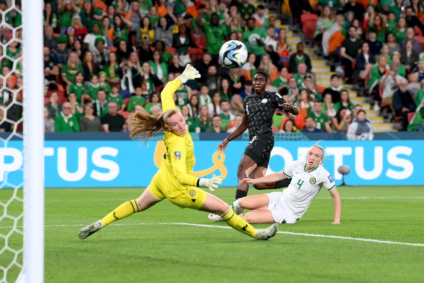 A Nigerian striker watches her shot fly by an Irish goalkeeper and defender, but wide of the post.
