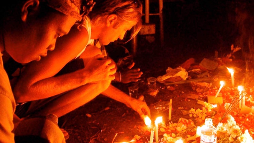 Grieving relatives light candles at a memorial service days after the Bali bombing.