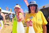 Two women holding water spray bottles and smiling.